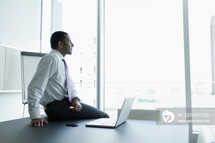 Thoughtful corporate businessman with laptop in conference room