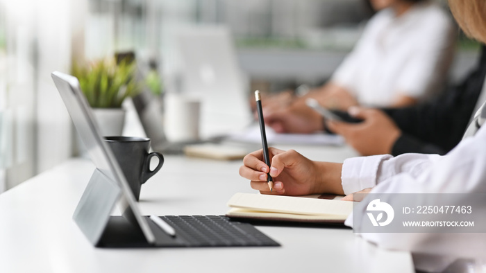 Close-up view of young businesswoman working on his plan writing the idea on notebook with digital t