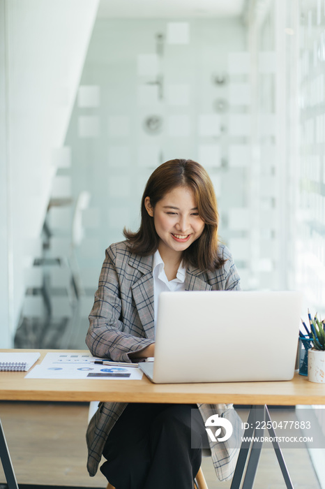 在笔记本电脑上工作的亚洲女性，在办公室里用笔记本电脑概念工作，年轻的亚洲女性