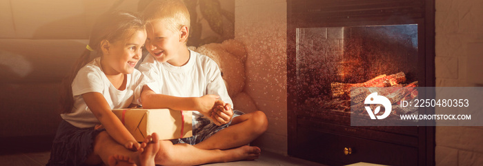 happy children with magic gift at home near fireplace