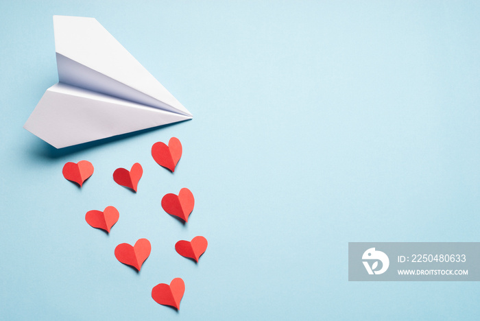 White paper plane pouring love. Love concept. Origami plane and paper hearts.