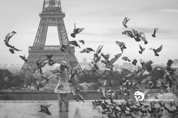 soft focus on tourist taking picture on eiffel tower with pigeons flying around