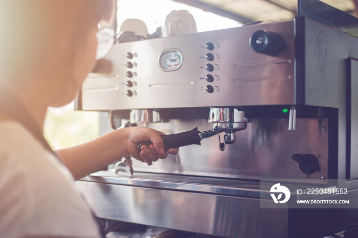 A woman who works in a coffee shop. She was making coffee with coffee machine.