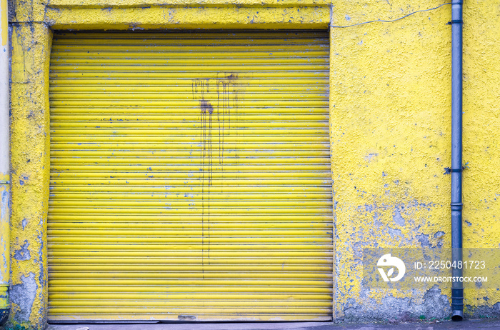 黄色卷帘门关闭的商业车库门和垃圾墙