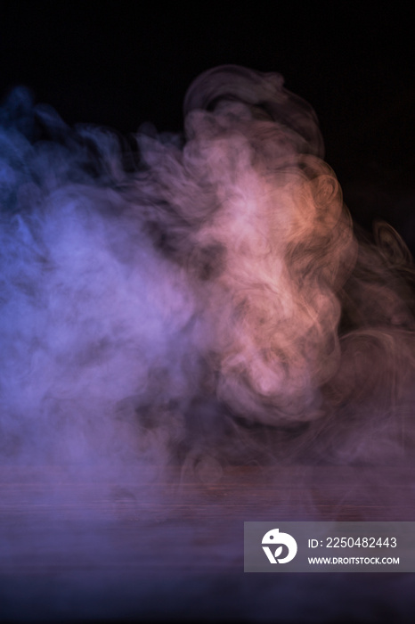 在深黑色背景和木桌上隔离的多色烟雾的概念图像。