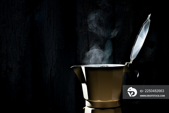 Moka pot with smoke on black background.soft focus.