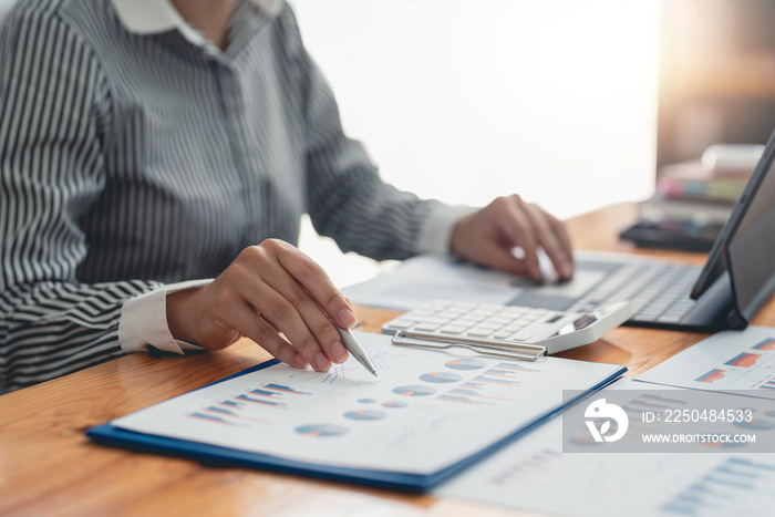 Businesswoman pointing pen at data graph, estimating profit and income statement of business in offi