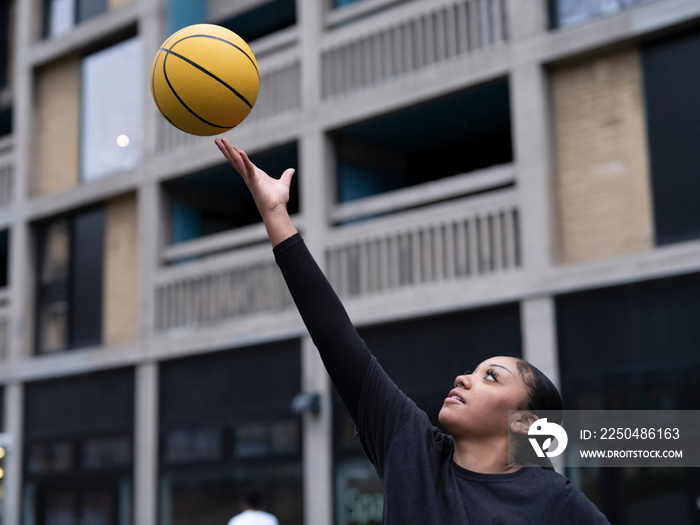 Teenage girl playing basketball outdoors