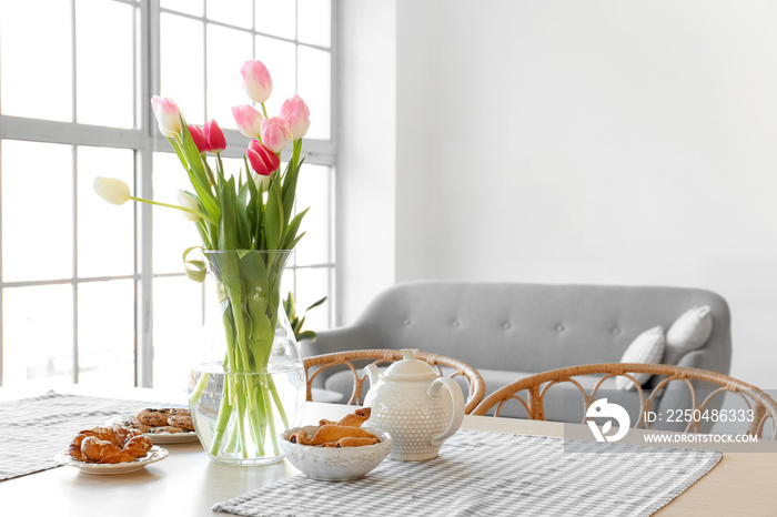 Vase with beautiful tulip flowers on dining table in room