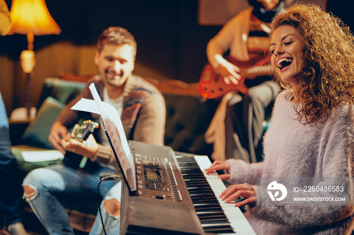 Woman playing clavier. Selective focus on woman. Home studio interior.