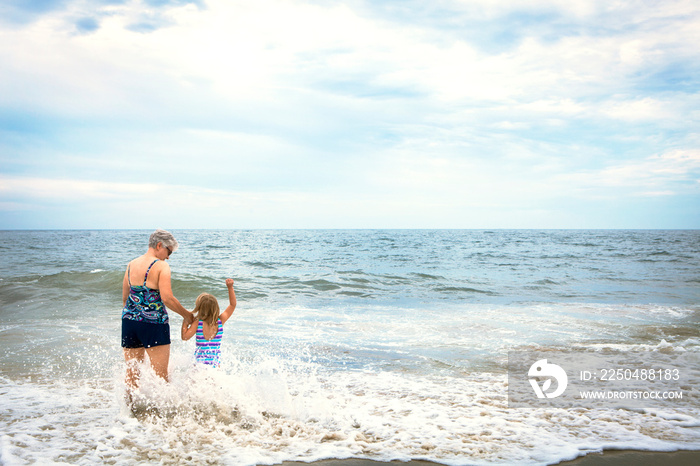 Woman with granddaughter (4-5) walking into sea