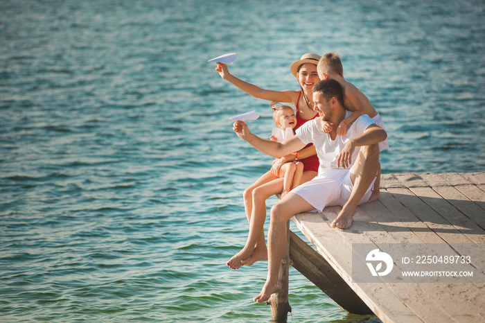 快乐快乐的一家人在水边的码头玩得很开心。可爱的孩子和他们的父母一起玩