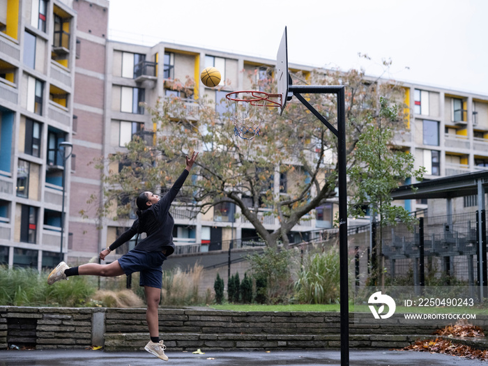 Teenage girl playing basketball outdoors