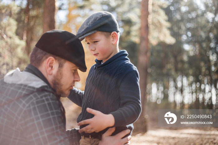 Father`s day. Sad son hugging dad on the  forest background  with copy space. Concept of father-son 