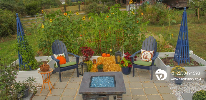 日落时的户外露台和凸起的花园床，用南瓜、植物和干草捆装饰秋季