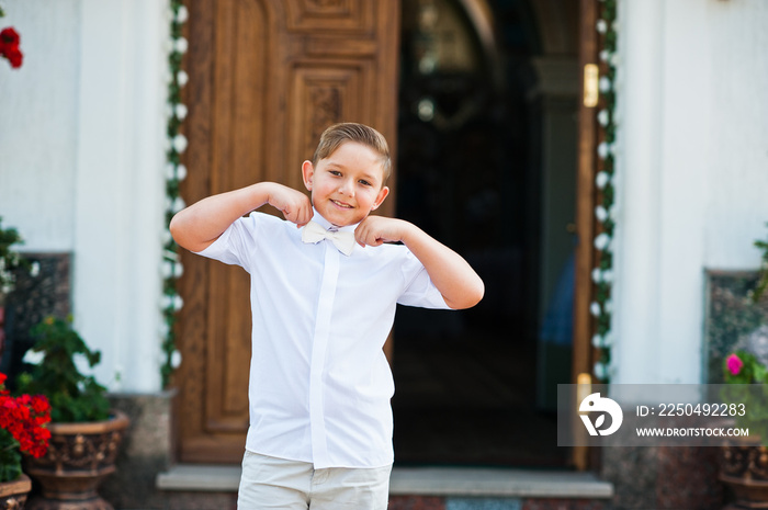 Portrait of little boy on white wear and bow tie on first holy c