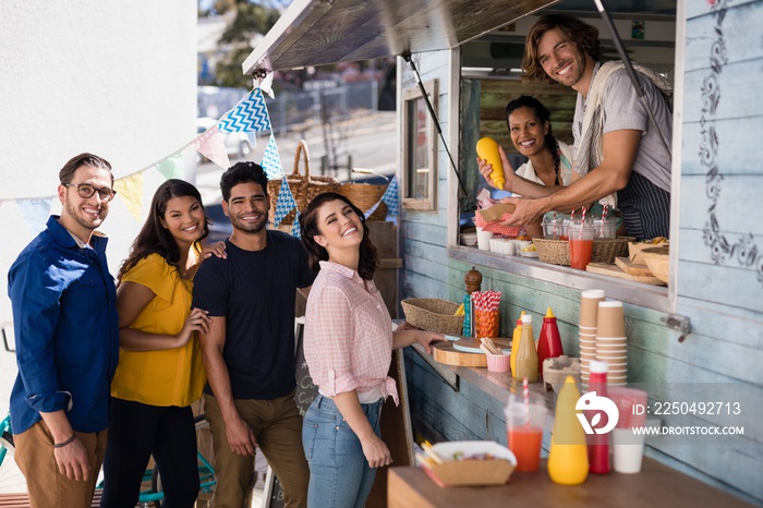 Smiling waiter giving order to customers at counter in food truc