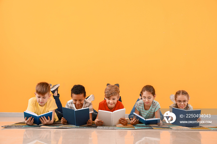 Cute little children reading books on color background