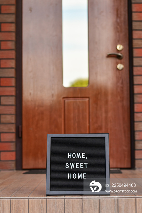 Home sweet home  sign on black letterbox standing next to the house entrance door.