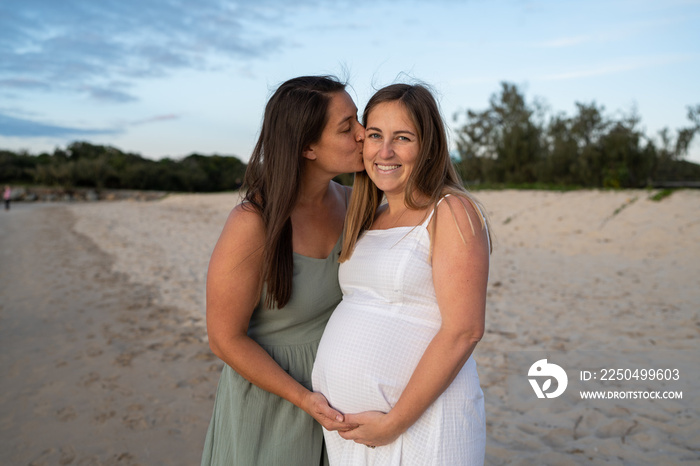 lesbian couple kissing on cheek at the beach