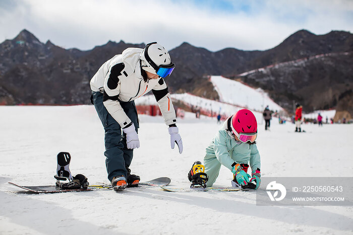 小女孩跟着教练在户外学滑雪