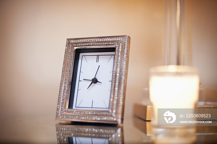 Close-up of candle and clock on end table against wall; Rancho Sante Fe; USA