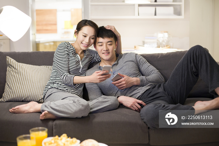 年轻情侣在客厅沙发上使用手机