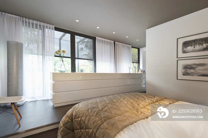 View of a bed along large window in bedroom at contemporary house