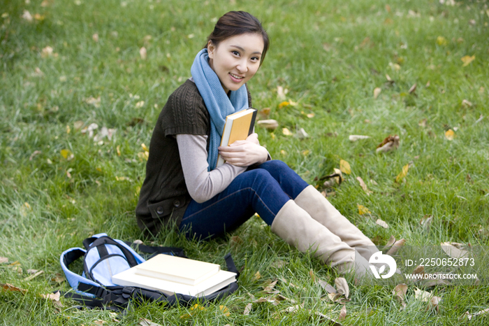 青年女子坐在草地上看书
