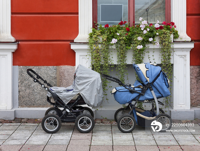 Two prams outside a house, under a window box