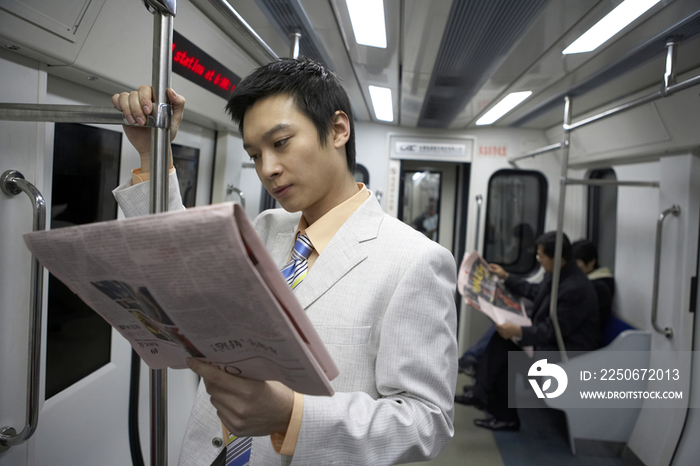 商务男士在地铁里看报纸