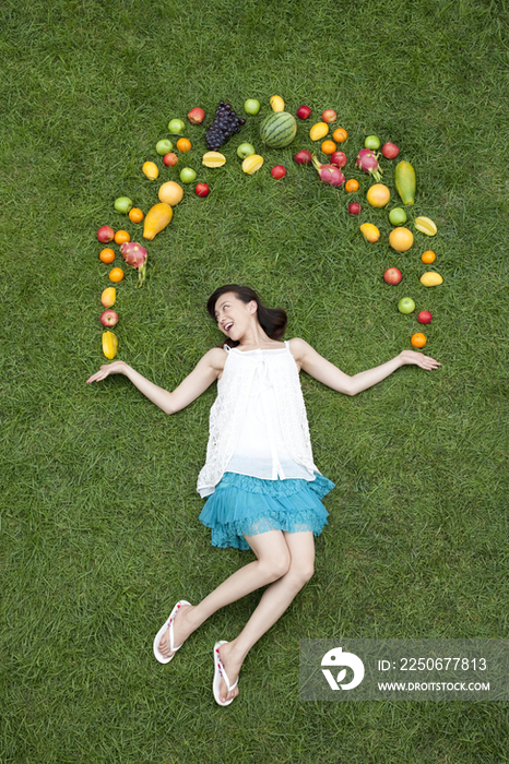 年轻女子和水果在草地上