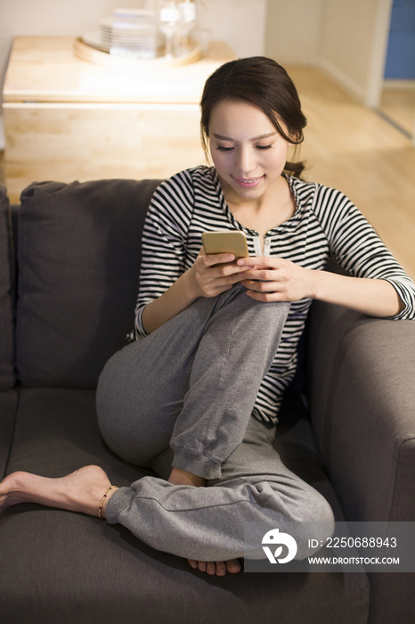 年轻女子在客厅沙发上使用手机