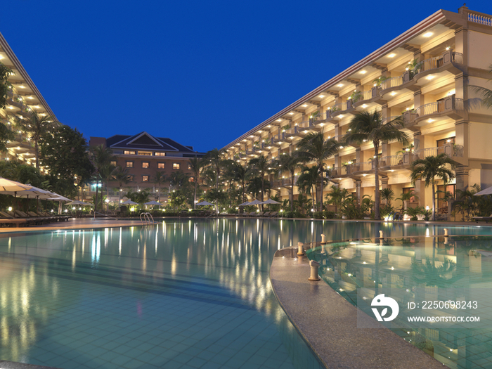 Illuminated hotel building with swimming pool at dusk