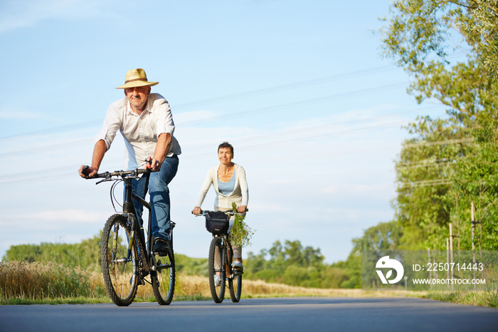 Senioren fahren mit Fahrrad durch Landschaft