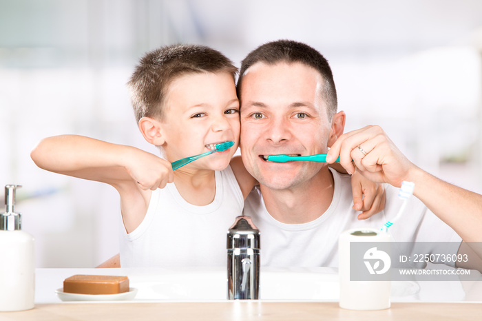 smiling child brushes his teeth with dad in the bathroom