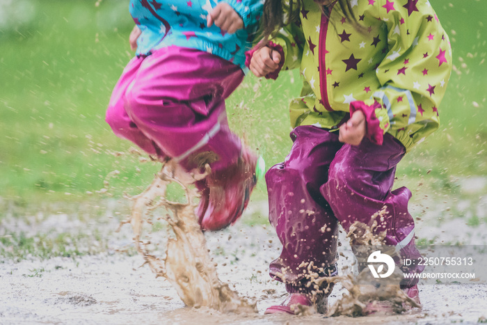 孩子们穿着胶靴和雨衣在水坑里跳。