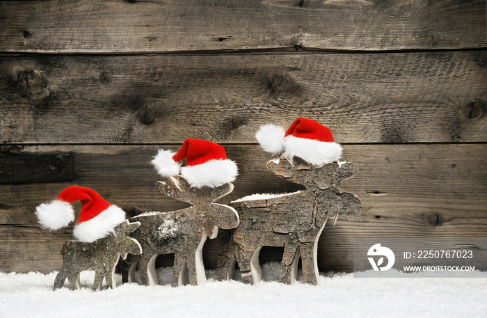 Three mooses wearing santa hats on grey wooden background