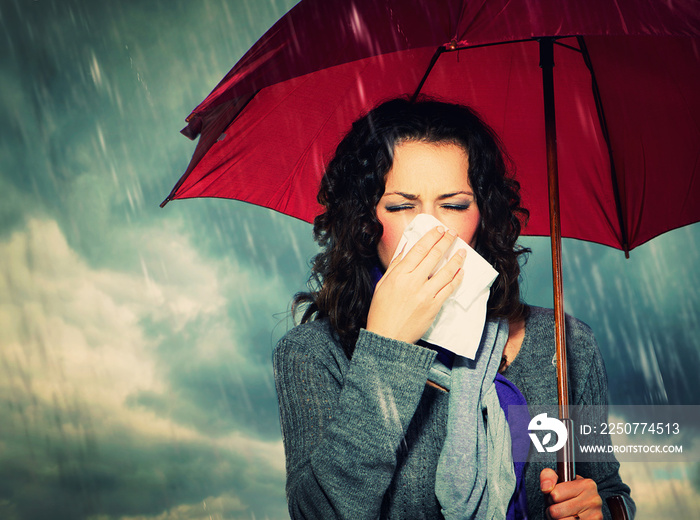 打着雨伞的打喷嚏女人在秋雨背景下