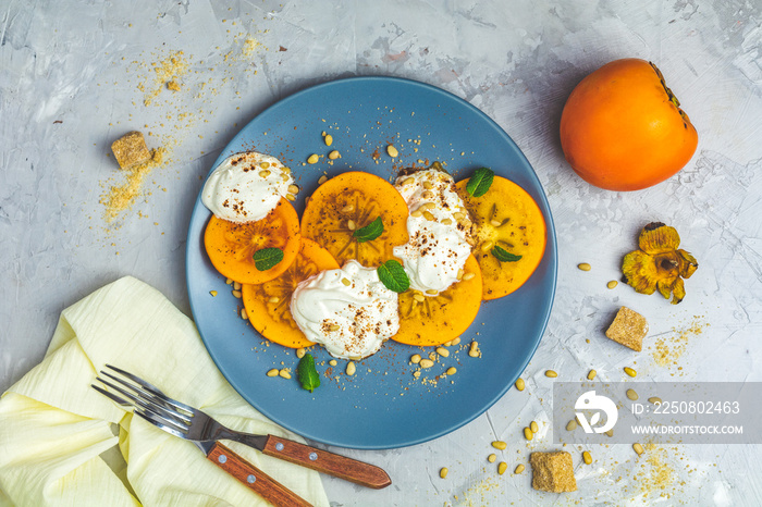 Sliced persimmon with yogurt, brown sugar, pine nuts and fresh mint