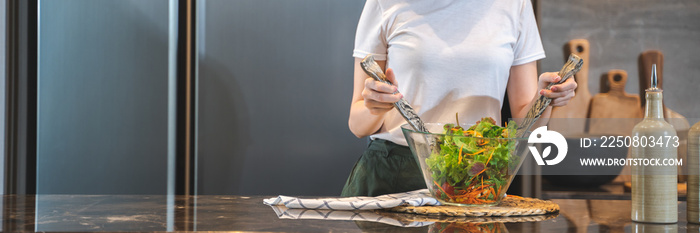 Happy young asian woman standing in kitchen and cooking healthy food. cook vegetable salad. Vegan Di