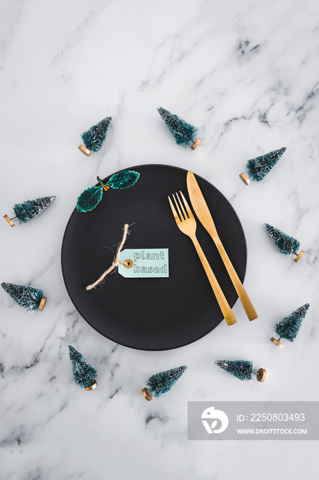 黑色餐盘顶部的植物标签，大理石桌子上到处都是圣诞装饰品