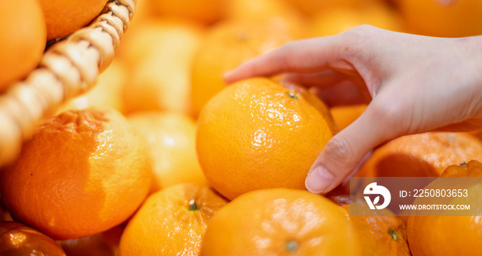 女性手拿着橙子在新鲜市场上制作橙汁，用于水果和蔬菜