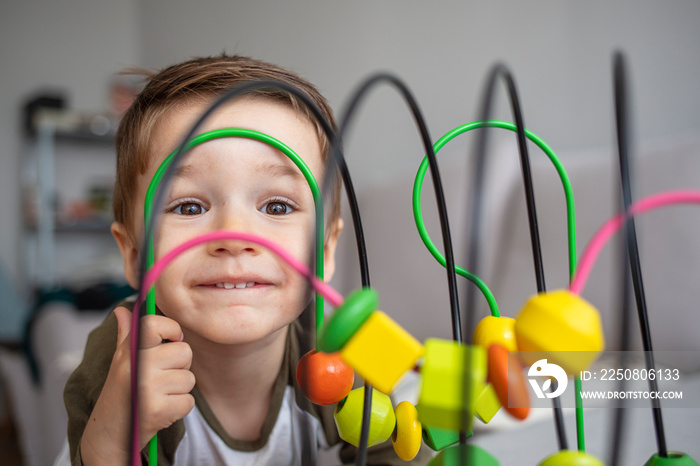 Little kid playing toys in the playroom. Kid toddler playing wooden toys at home or nursery. Beautif