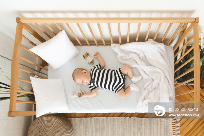 Adorable baby sleeping in crib with toy in his hand