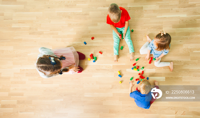 Top view of four kids constructing of wooden blocks