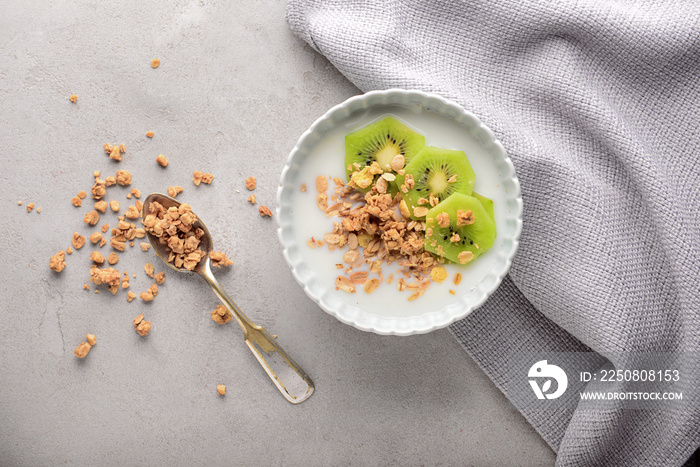 Tasty granola with yogurt in bowl on grey table