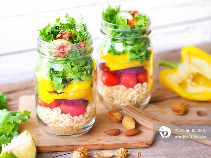 Vegan salad jar with green oak, yellow bell peppers beetroot, cherry tomato, and brown rice on a rus