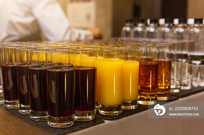 Rows of glasses with non alcoholic drinks, orange juice and water. Drinks on a buffet table. Caterin