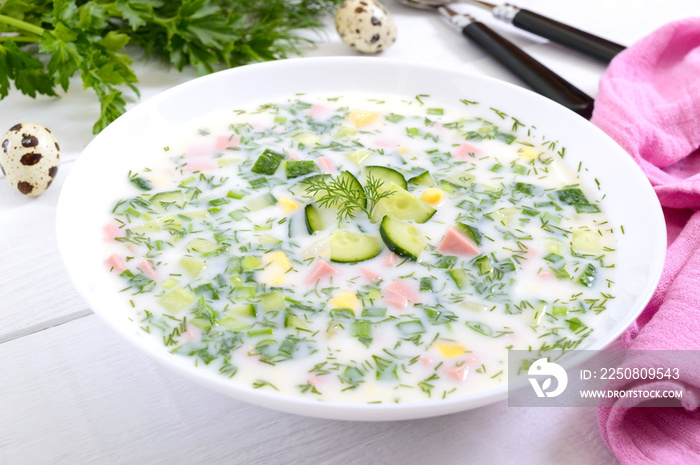 Cold summer soup okroshka. Light soup in a white bowl.